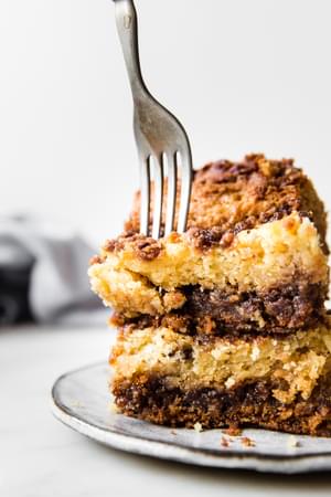 a fork cutting into a piece of sour cream coffee cake on a grey plate
