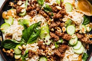 Cold Thai noodle salad topped with peanut dressing, crushed peanuts, ground pork, cucumbers, basil and mint