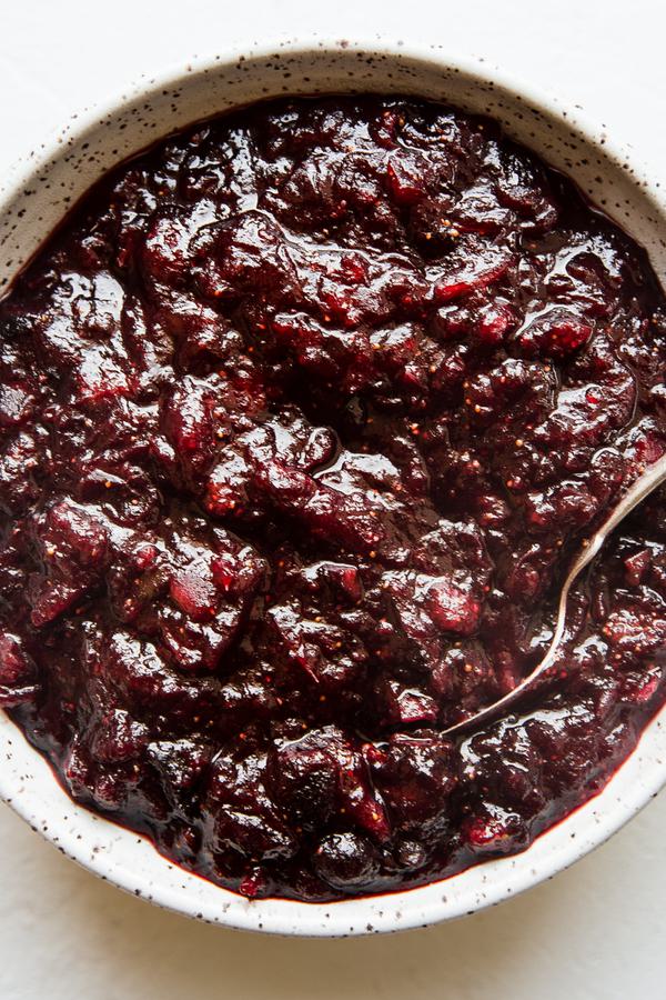 A bowl of cranberry chutney with a serving spoon