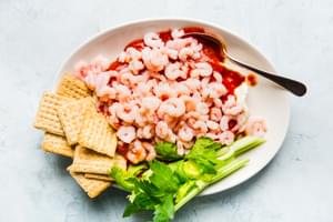 cream cheese shrimp dip on a white platter with triscuits and celery