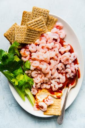 cream cheese shrimp dip on a white platter with triscuits and celery