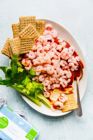 cream cheese shrimp dip on a white platter with crackers and celery