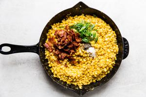 raw corn kernels , salt, pepper, green onions, and bacon being cooked in bacon fat in a skillet