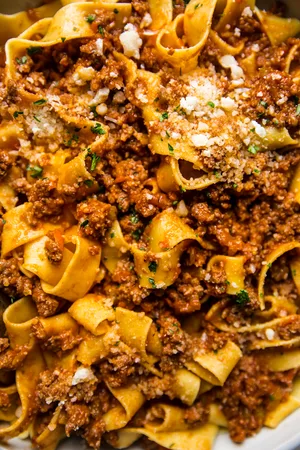 close up photo of homemade bolognese topped with parmesan cheese and fresh parsley