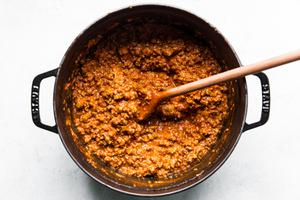 homemade bolognese in a large pot with a wooden spoon