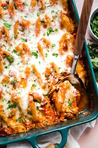 Easy Stuffed Pasta Shells in a pan with tomato sauce and mozzarella with a serving spoon