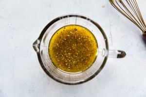 Italian salad dressing being made with olive oil, red wine vinegar, garlic powder, dried oregano & basil and salt
