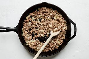 ground beef, garlic and onion being cooked in a skillet