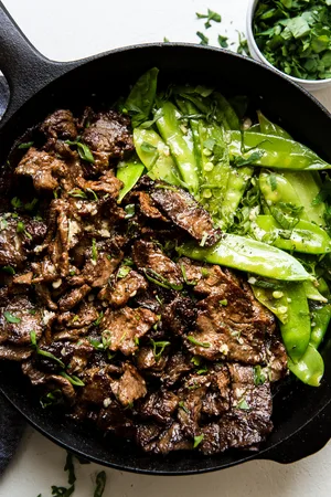 Garlic Butter Steak Stir-Fry with snappy peas in a cast iron pan