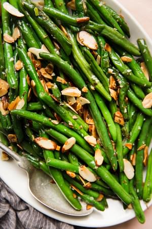 green bean almondine on a white platter
