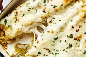 homemade green chicken enchiladas in a casserole dish made with chicken, cheese, sour cream and taco seasoning