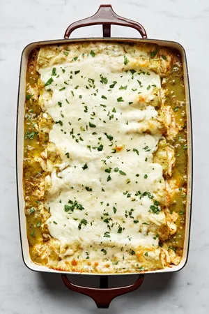 homemade green chicken enchiladas in a casserole dish made with chicken, cheese, sour cream and taco seasoning