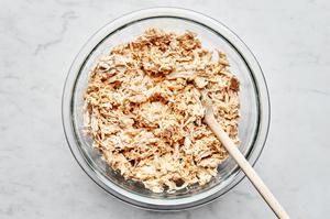 shredded chicken, shredded cheese, taco seasoning and sour cream being stirred in a bowl to make enchilada filling