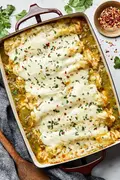 homemade green chicken enchiladas in a casserole dish made with chicken, cheese, sour cream and taco seasoning