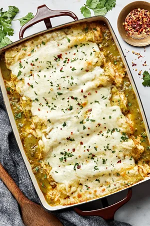 homemade green chicken enchiladas in a casserole dish made with chicken, cheese, sour cream and taco seasoning