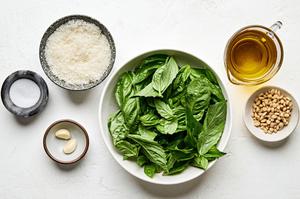 basil, Parmesan, pine nuts, cloves, sea salt and olive oil in bowls to make basil pesto