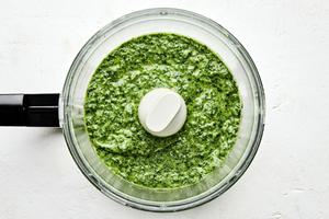 basil pesto in a food processor made with basil, Parmesan, pine nuts, cloves, sea salt and olive oil
