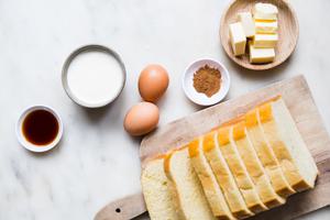 sliced brioche, eggs, cinnamon, butter, heavy cream cream and vanilla in bowls on the counter to make home made French toast