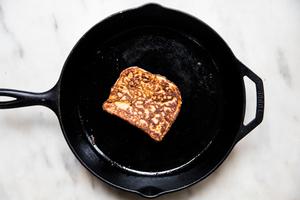 a slice of brioche bread soaked in egg and cream batter being fried in a skillet for French toast