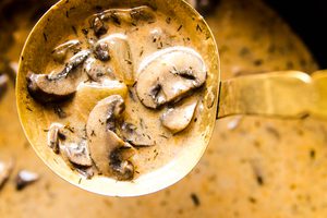 Creamy  Hungarian mushroom soup garnished with fresh parsley being ladled out of a pot for a cozy vegetarian meal.