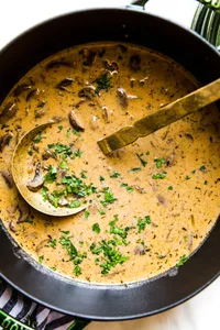 A large pot of Hungarian mushroom soup garnished with fresh parsley. A hearty vegetarian fall meal.