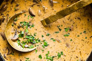 A large pot of Hungarian mushroom soup garnished with fresh parsley. A hearty vegetarian fall meal.