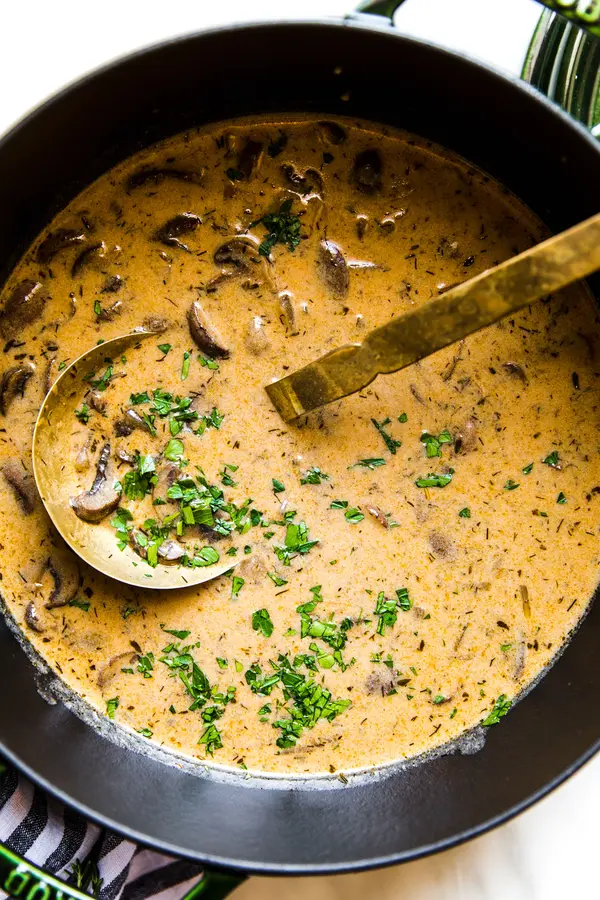 A large pot of Hungarian mushroom soup garnished with fresh parsley. A hearty vegetarian fall meal.