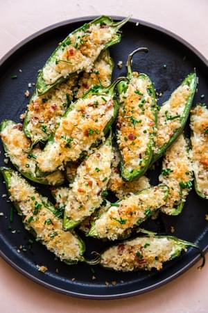 black plate with homemade jalapeno poppers topped with bacon and buttery panko crumbs