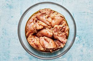 chicken thighs seasoned with salt in a bowl with marinade made with olive oil, jerk seasoning and lime juice
