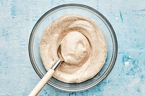mayonnaise, lime juice and jerk seasoning being stirred together in a glass bowl to make jerk aioli
