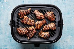jerk marinated chicken thighs being cooked on a grill