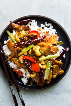 Easy, Homemade Kung Pao Chicken stir fry with tender chicken pieces,  cashews, & bell peppers served over white rice