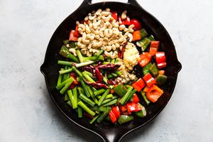 bell peppers, green onions, cashews, ginger, garlic, and dried chili peppers cooking in sesame oil in a skillet