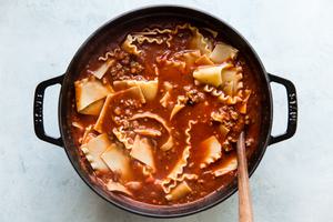 lasagna soup in a soup pot with a wooden spoon.