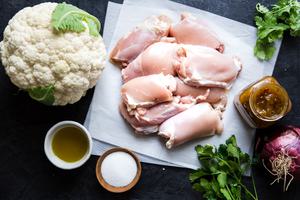 ingredients laid out chicken thighs, cauliflower, olive oil, salt, cilantro and red onion