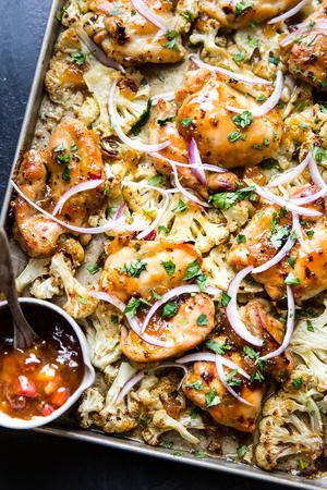 Mango Chutney Sheet Pan Chicken With Cauliflower on a baking sheet with red onion and cilantro