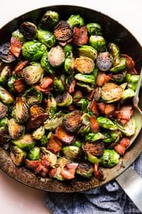skillet of crispy maple bacon brussels sprouts seasoned with salt and pepper
