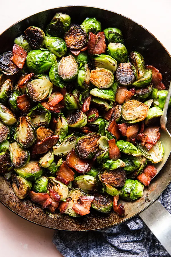 skillet of crispy maple bacon brussels sprouts seasoned with salt and pepper