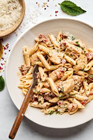 a bowl of marry me chicken pasta made with garlic, cream, Parm, sun dried tomatoes, italian seasoning topped with fresh basil