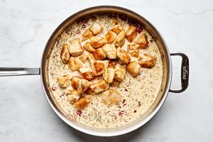 browned chicken added to a pan of creamy sun-dried tomato and Parmesan sauce