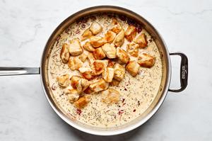 browned chicken added to a pan of creamy sun-dried tomato and Parmesan sauce
