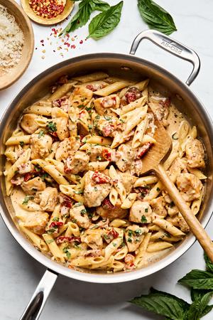 a pan of marry me chicken pasta made with sun-dried tomatoes, cream, Parmesan & Italian seasoning sprinkled with fresh basil