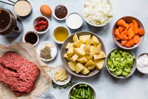potatoes, vegetables, ground beef, spices, olive oil and beef broth in bowls on the counter to make meatball stew