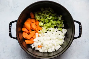 olive oil, onions, celery and carrots being cooked in a pot for meatball stew