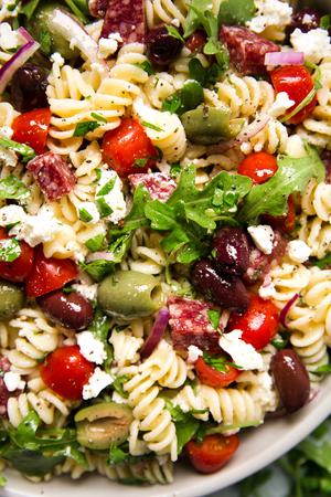 close up of Mediterranean Pasta Salad in a bowl with feta, olives, tomatoes and arugula