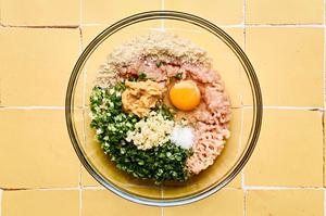 ground chicken, cilantro, green onions, panko, egg, white miso, garlic, and salt being mixed together in a glass bowl