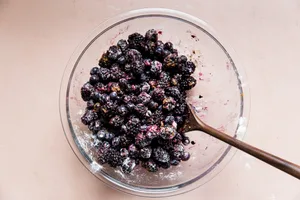 mixed berries being stirred in a bowl with sugar, salt, flour, lemon juice and cinnamon