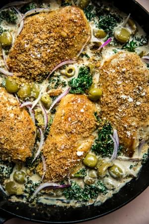 one-pot chicken with creamed kale topped with Castelvetrano  olives and toasted panko breadcrumbs in a skillet on the counter