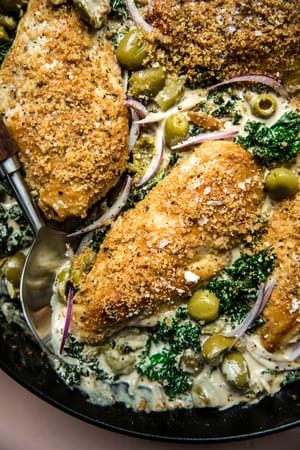 one-pot chicken with creamed kale topped with Castelvetrano  olives and toasted panko breadcrumbs in a skillet on the counter