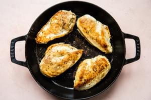 chicken breast seasoned with salt and pepper being browned in olive oil in a skillet